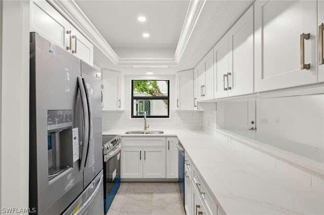 kitchen with tasteful backsplash, sink, stainless steel appliances, white cabinets, and light stone counters