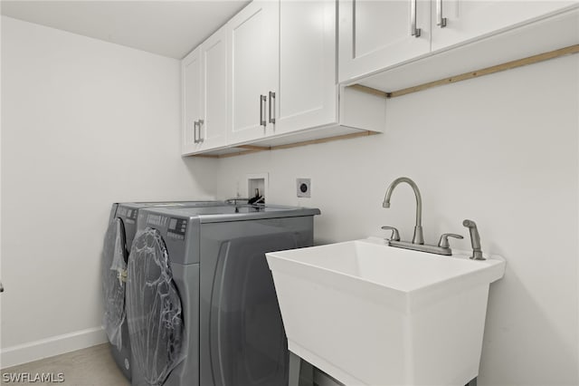 clothes washing area with washer and dryer, sink, and cabinets