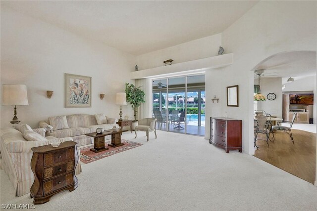 living room with carpet, ceiling fan, and high vaulted ceiling