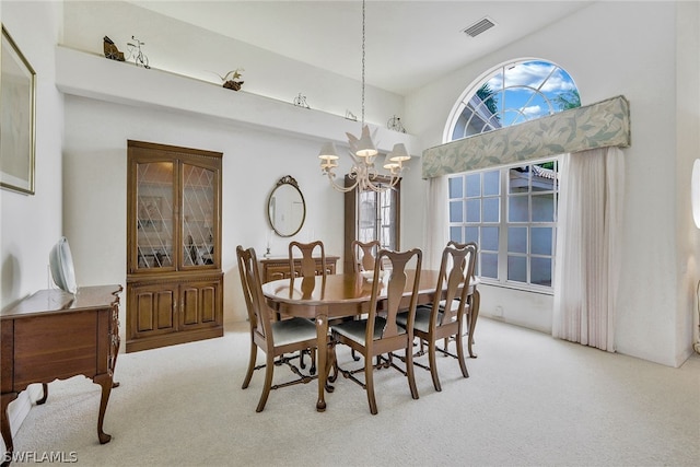 carpeted dining space with a towering ceiling and a chandelier