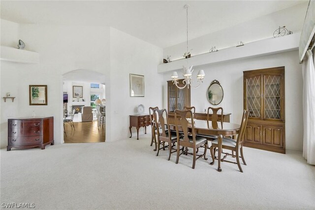 carpeted dining area with an inviting chandelier and high vaulted ceiling