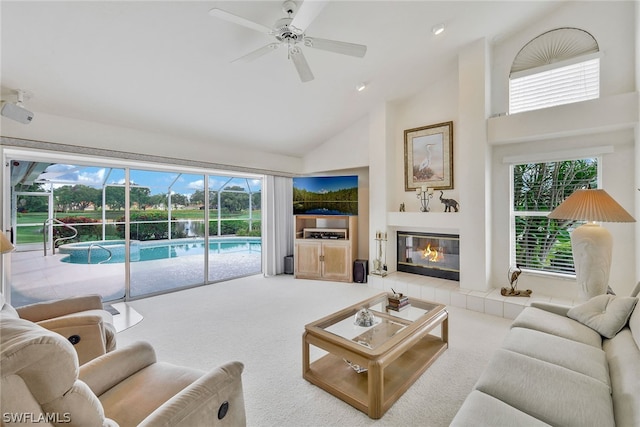 carpeted living room featuring a fireplace, high vaulted ceiling, and ceiling fan