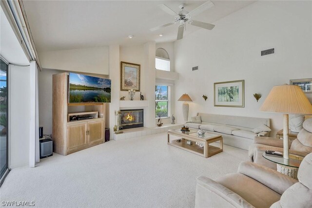 living room featuring high vaulted ceiling, a tile fireplace, carpet floors, and ceiling fan