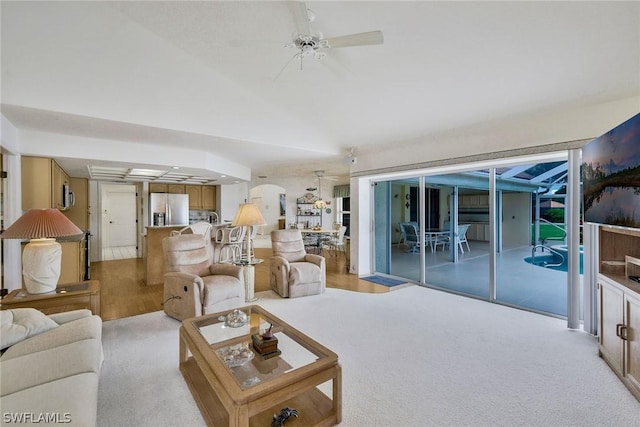 living room with ceiling fan, vaulted ceiling, and light hardwood / wood-style floors