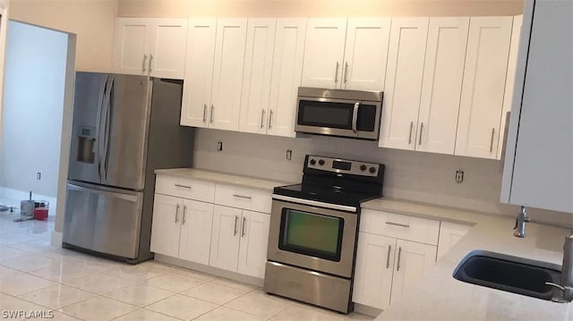 kitchen with appliances with stainless steel finishes, white cabinetry, tasteful backsplash, and sink