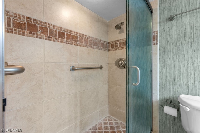 bathroom with a shower with shower door and toilet