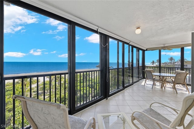 sunroom / solarium featuring a water view and a view of the beach