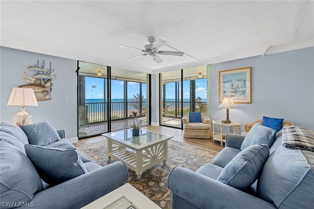 living room featuring expansive windows, a water view, crown molding, ceiling fan, and wood-type flooring