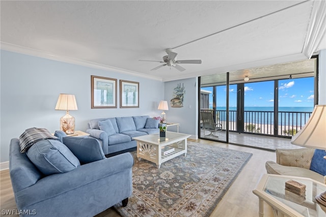 living room featuring expansive windows, a water view, ceiling fan, light wood-type flooring, and ornamental molding