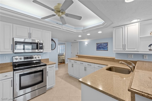 kitchen featuring stainless steel appliances, a raised ceiling, white cabinetry, and sink