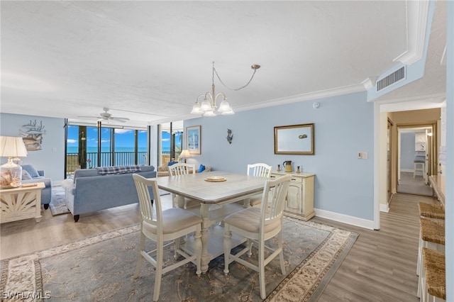 dining space with floor to ceiling windows, ceiling fan with notable chandelier, a water view, crown molding, and hardwood / wood-style flooring