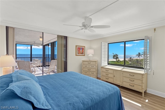 bedroom featuring ceiling fan, hardwood / wood-style floors, access to outside, a water view, and ornamental molding