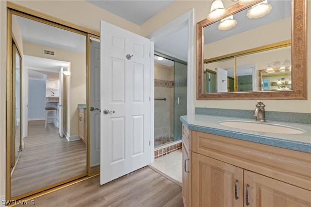 bathroom with a shower with door, vanity, and hardwood / wood-style floors