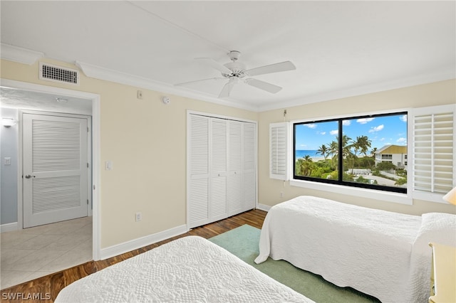 tiled bedroom featuring ceiling fan, ornamental molding, and a closet