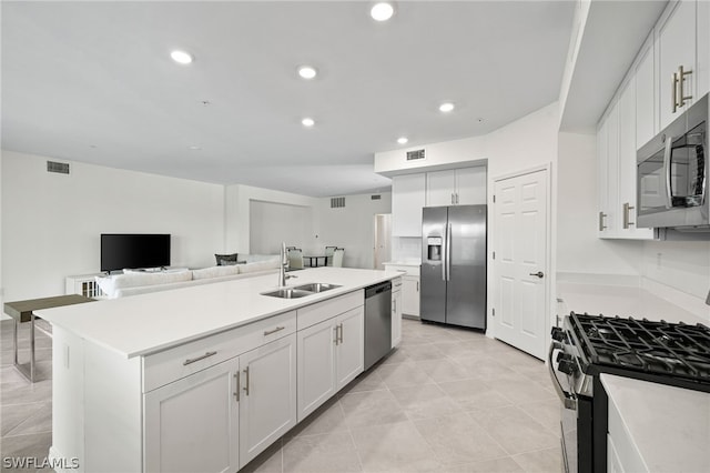 kitchen with a kitchen island with sink, sink, light tile patterned floors, white cabinetry, and stainless steel appliances