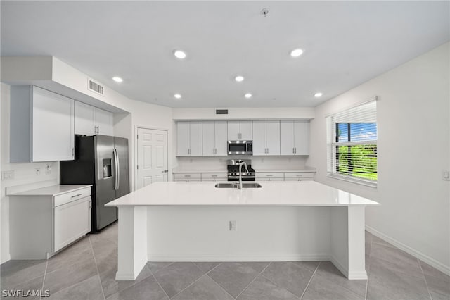 kitchen featuring sink, an island with sink, light tile patterned floors, and appliances with stainless steel finishes