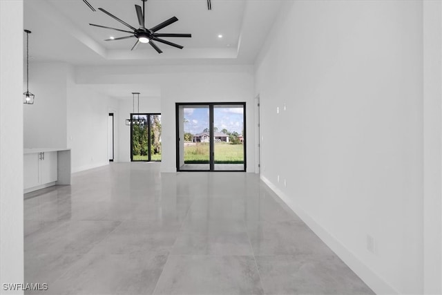 empty room with ceiling fan and a raised ceiling