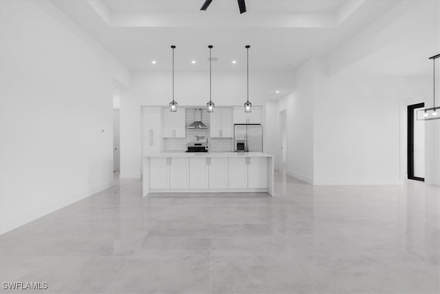 kitchen with white cabinets, wall chimney range hood, a large island, decorative light fixtures, and stainless steel refrigerator with ice dispenser