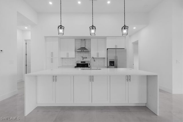 kitchen with stainless steel appliances, wall chimney exhaust hood, hanging light fixtures, white cabinetry, and a large island