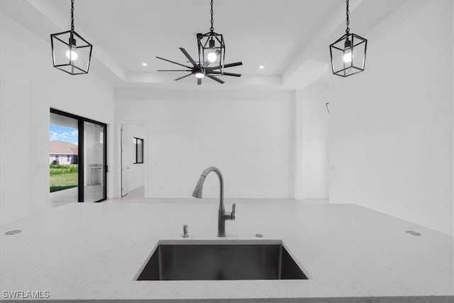 kitchen featuring a tray ceiling, decorative light fixtures, and sink