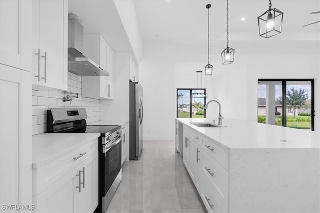 kitchen with stainless steel appliances, wall chimney range hood, sink, and white cabinetry