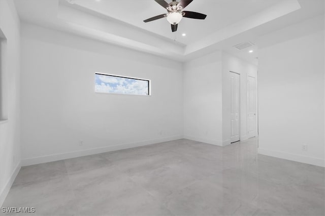 empty room featuring ceiling fan and a tray ceiling