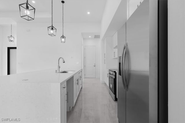 kitchen featuring white cabinets, appliances with stainless steel finishes, hanging light fixtures, and sink