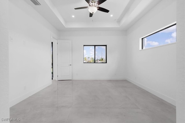 spare room with ceiling fan and a tray ceiling