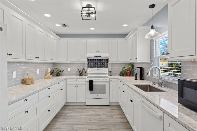 kitchen with light stone counters, white appliances, sink, white cabinets, and hanging light fixtures