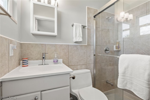 bathroom with vanity, toilet, a shower with door, and tile walls