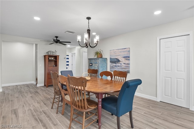 dining space with ceiling fan with notable chandelier and light hardwood / wood-style flooring