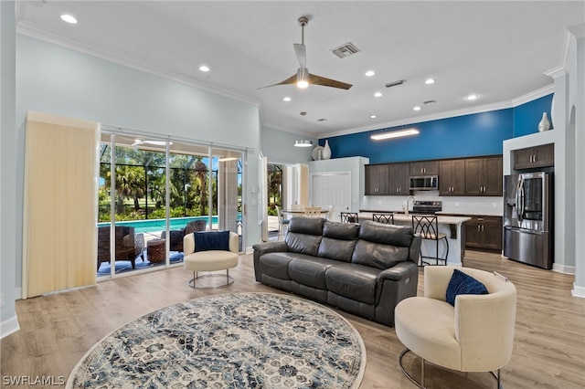 living room with light hardwood / wood-style flooring, ceiling fan, and crown molding