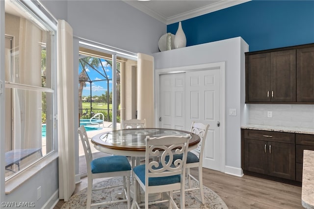 dining space with light wood-type flooring, plenty of natural light, and ornamental molding