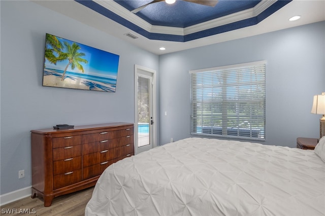 bedroom with access to exterior, ceiling fan, a raised ceiling, light hardwood / wood-style floors, and ornamental molding