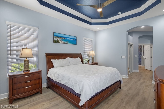 bedroom featuring a tray ceiling, crown molding, ceiling fan, and light hardwood / wood-style floors