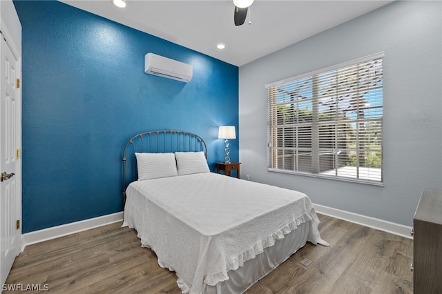 bedroom featuring a wall mounted air conditioner, ceiling fan, and hardwood / wood-style floors