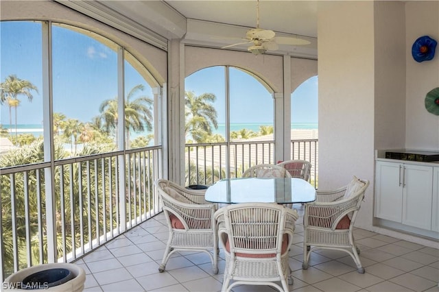 sunroom / solarium with ceiling fan, a water view, and a healthy amount of sunlight