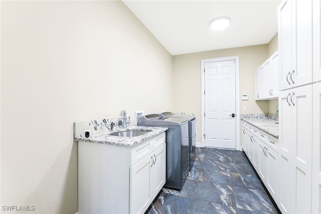 clothes washing area featuring washing machine and dryer, cabinets, and sink