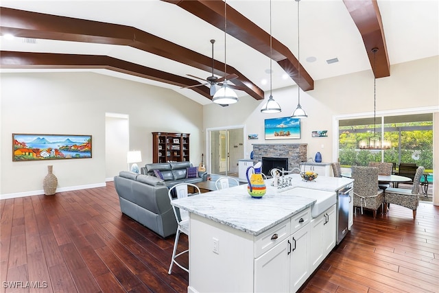 kitchen featuring decorative light fixtures, a fireplace, a kitchen island, white cabinetry, and light stone counters