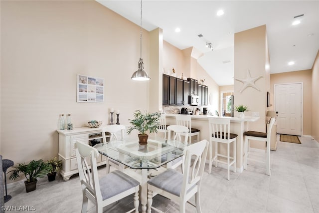 tiled dining space featuring high vaulted ceiling