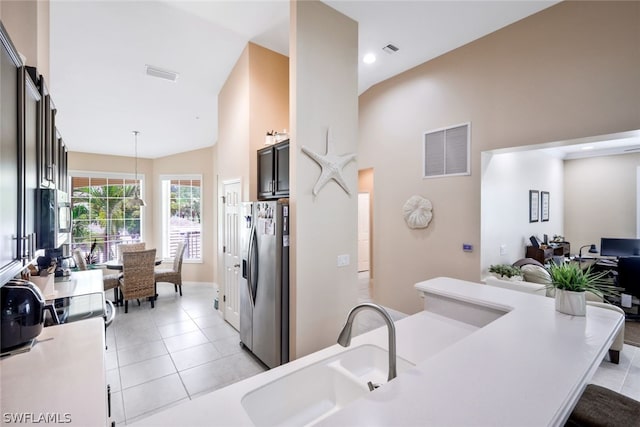 kitchen with sink, pendant lighting, high vaulted ceiling, stainless steel fridge with ice dispenser, and light tile patterned flooring