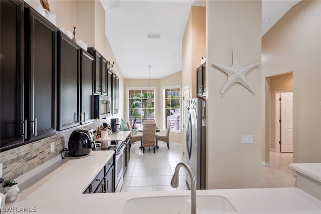 kitchen featuring sink, hanging light fixtures, backsplash, light tile patterned flooring, and appliances with stainless steel finishes