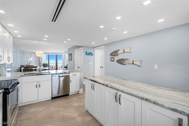 kitchen with white cabinets, appliances with stainless steel finishes, light stone countertops, and sink