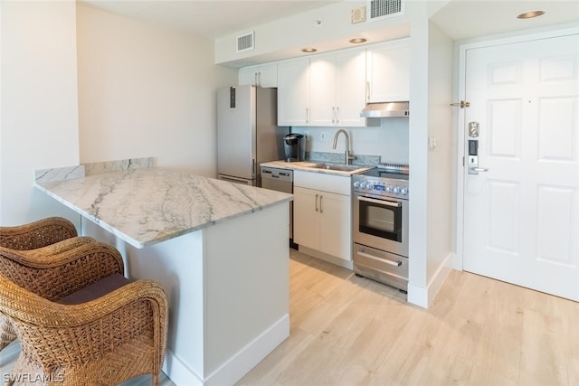 kitchen featuring appliances with stainless steel finishes, sink, white cabinetry, kitchen peninsula, and a breakfast bar area