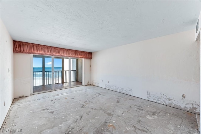 empty room with a textured ceiling and a water view