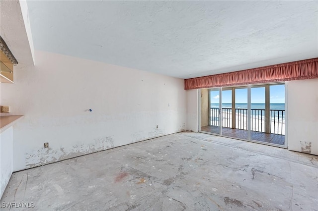 spare room featuring a textured ceiling and a water view