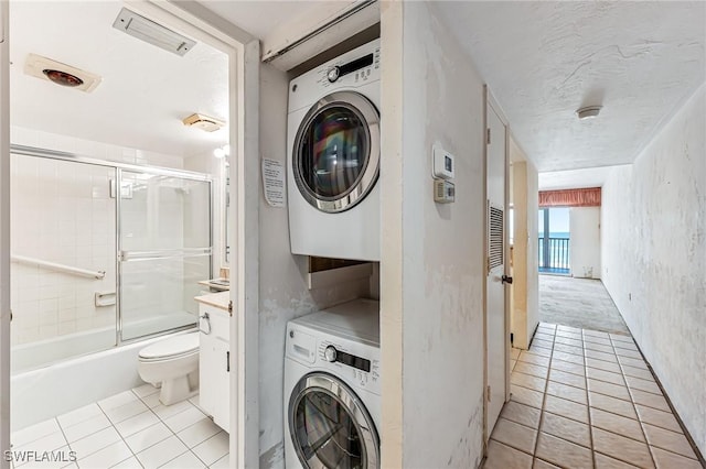 laundry area with stacked washer / drying machine, a textured ceiling, light tile patterned flooring, and laundry area