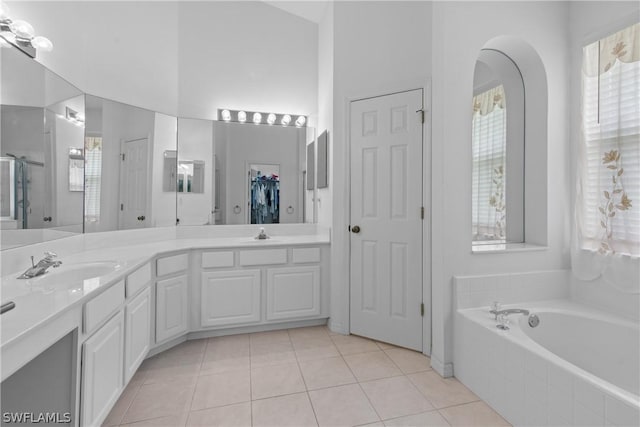 bathroom featuring a towering ceiling, vanity, a shower with shower door, and tile patterned flooring