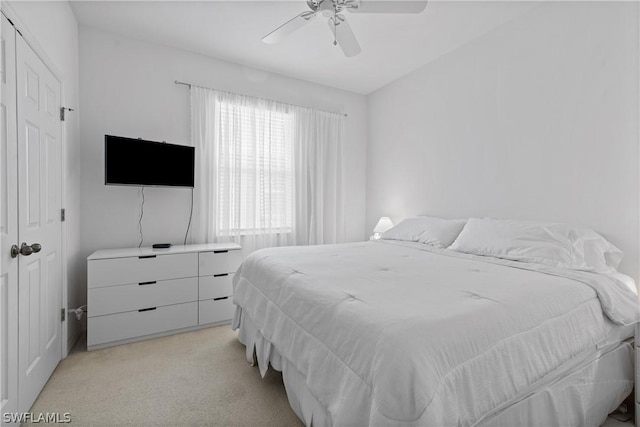 bedroom featuring ceiling fan, a closet, and light colored carpet