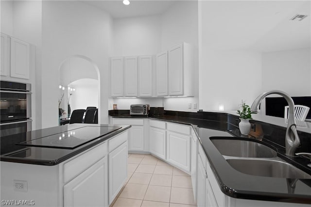 kitchen with black electric stovetop, sink, a kitchen island, and white cabinets